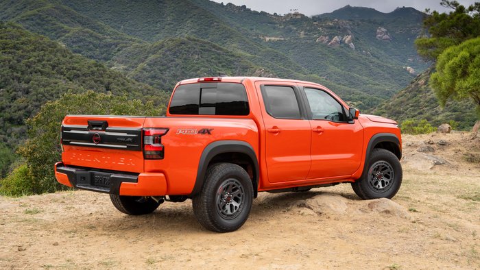 Rear View of orange Nissan Frontier driving off-road.