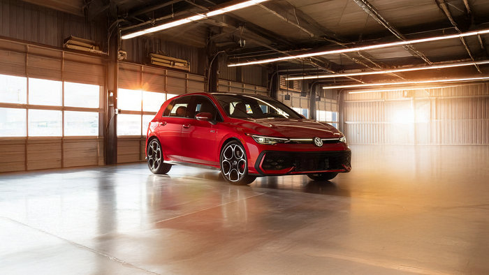 Front side view of a red Volkswagen Golf GTI parked in a garage.