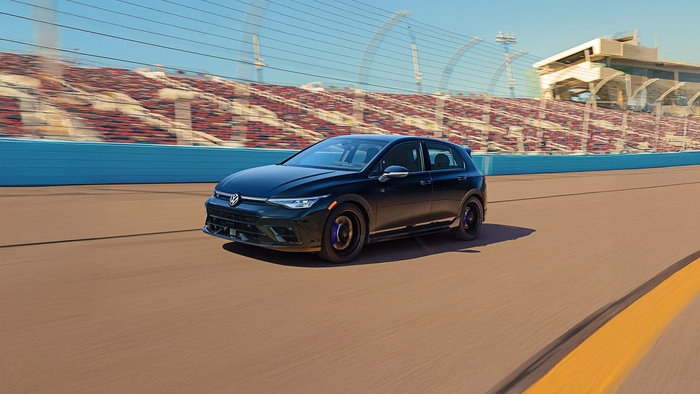 Front view of a black Volkswagen Golf R driving on a track..