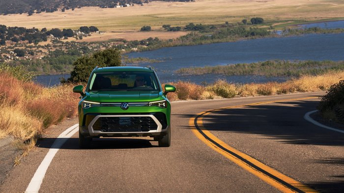 Front view of green Volkswagen Taos driving on a road.
